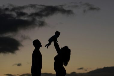 a silhouette of a man and a woman holding a baby